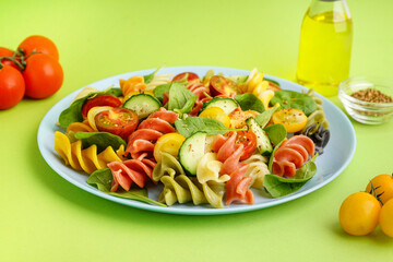 Plate with Italian pasta salad on green background