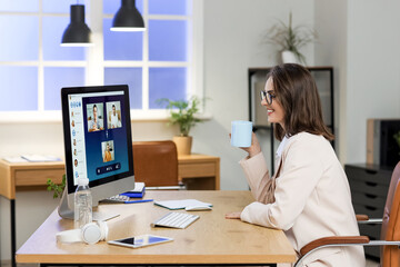 Young businesswoman with coffee cup video chatting in office at night