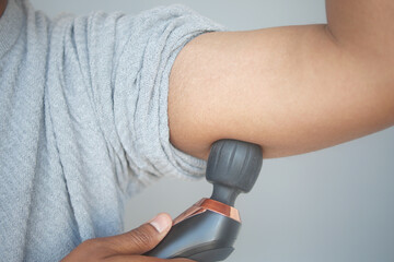 Individual Applying a Massage Gun to Their Arm for Effective Muscle Relaxation and Relief