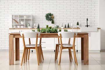 Modern interior of dining room with Christmas mistletoe wreath, candles and glasses