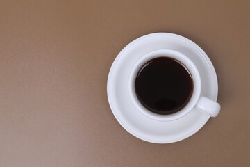 Black coffee in a white cup on a brown table
