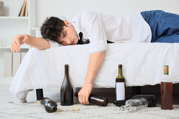 Drunk young businessman lying on bed. Alcoholism concept