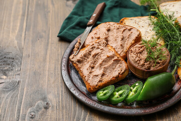 Toasts with tasty pate, jalapeno pepper slices, dill and knife on wooden background