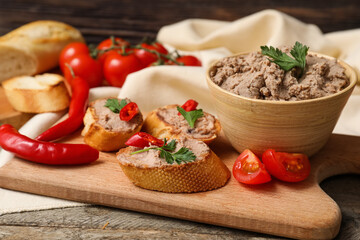 Board with toasts, bowl of tasty pate, parsley, chilli peppers and tomatoes on wooden background