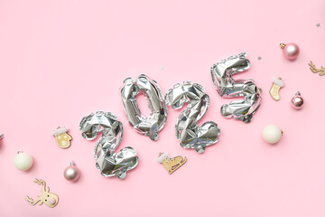 Figure 2025 made of foil balloons and Christmas decorations on pink background