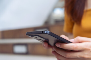 Woman holding smartphone while walking in the urban city. The concept of using the phone is essential in everyday life.