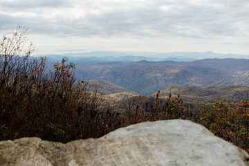 Beautiful autumn landscape with rocks, mountains and forest with yellow and red leaves on trees. Road among mountains in North Carolina, USA.