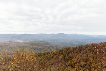 Beautiful autumn landscape with rocks, mountains and forest with yellow and red leaves on trees. Road among mountains in North Carolina, USA.
