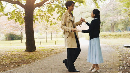 Love, dance and holding hands with Japanese couple in park for romance, bonding and relationship. Support, care and happiness with man and woman in Japan nature for date, commitment and peace