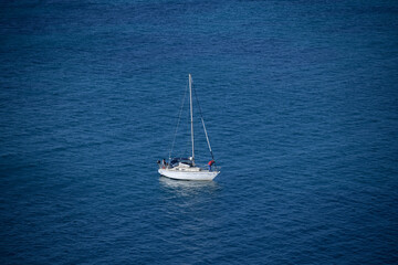 Yacht moored in blue ocean, man checks the anchor