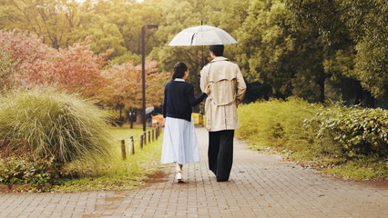 Date, back and umbrella with couple walking in park for romance, bonding and relationship. Support,...