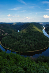 Winding river through hills with green trees on the Saar River in Germany.