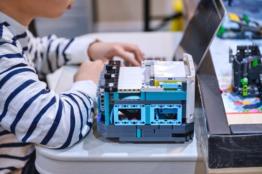 Student is coding, programming and designing robot in a robotics class. Kids STEM education and innovation concept background.