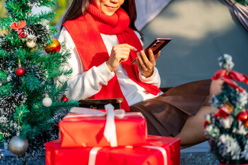 Happy young woman using smartphones with Christmas ornaments in the garden, Merry Christmas concept