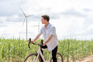 Caucasian active casual man riding bicycle at the windmill power farm. 