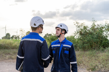 Technicians man making handshake while work in the wind turbines field. 