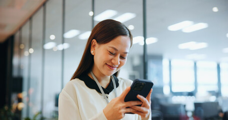 Fototapeta premium Cellphone, happy and businesswoman in office with email, networking or communication for investment. Technology, contact and Japanese female financial planner with phone for online finance report.