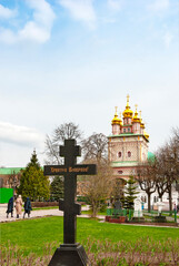 Christ is Risen. The inscription on the grave cross in the Trinity-Sergius Lavra against the background of the gate church of the Nativity of John the Baptist. Sergiev Posad city