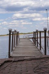 Obraz premium Wooden pier with wooden fencing on the bank of the Vorskla River. Landscape with a fishing pier on the river