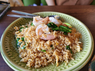 Delicious shrimp fried rice with vegetables on green plate, showcasing vibrant meal. dish features fluffy rice, succulent shrimp, and fresh greens, perfect for satisfying lunch