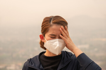 Asian woman having headache becaused of by Bad air pollution (PM2.5).