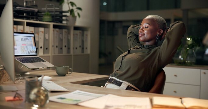 Black woman, relax and night with break at office for done, finished or completion by desk. African, female person or employee with smile for rest, productive evening or deadline accomplishment