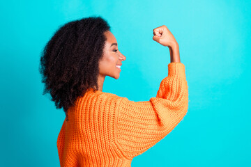 Photo portrait of lovely young lady show biceps flexing dressed stylish knitted orange garment isolated on aquamarine color background