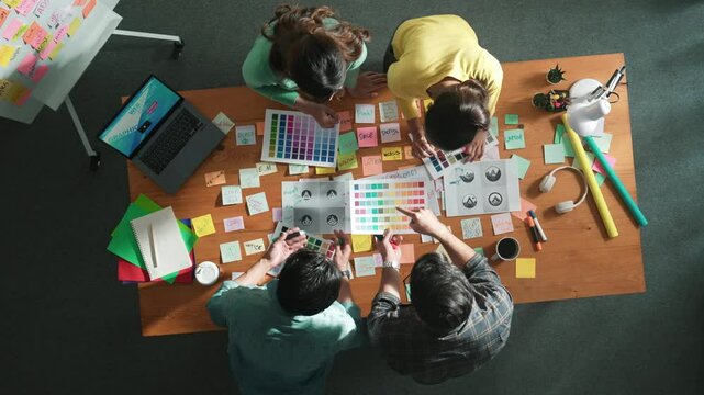 Top view of smart manager holding and looking at color palettes and choose color for logo or product. Aerial view of business team working together brainstorm appropriate theme for project. Symposium.