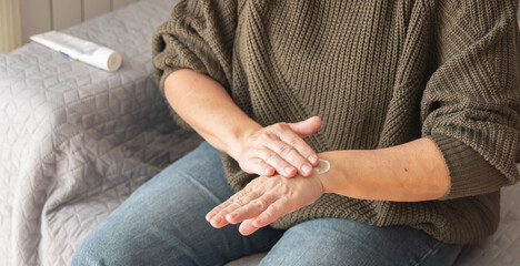 Fototapeta premium Mature Woman’s Hands Gently Applying Hydrating Cream As Part Of A Daily Anti-Aging Skincare Routine For Glowing, Healthy Skin
