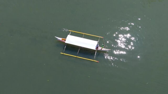 A small passenger pump boat glides across calm waters on a sunny day in Tagana-an, aerial view