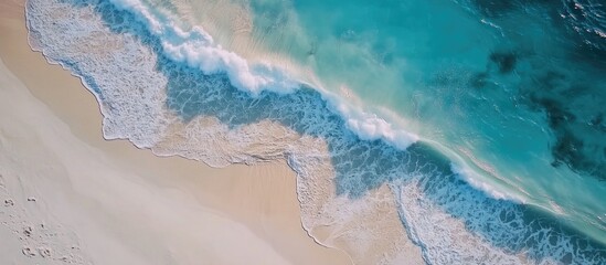 Aerial view of ocean waves crashing onto a pristine white sand beach with crystal clear seawater inspiring a fresh start and challenges ahead