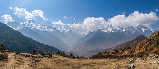 Obraz premium Majestic panoramic view of snow-capped mountains under a clear blue sky with lush valleys and rocky terrain in breathtaking wilderness.
