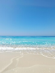 Fototapeta premium Fine sandy beach with gentle blue ocean wave under a clear blue sky, peaceful shoreline, sunny day.