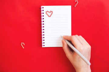 Child hand with holding pen on white paper blank notebook and writing wish list.