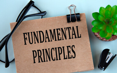 FUNDAMENTAL PRINCIPLES - words on brown paper on a light background with glasses, cactus and stapler