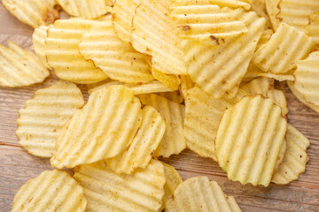 木のテーブルに広がるギザギザポテトチップスの俯瞰