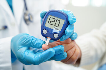 Asian doctor using digital glucose meter for check sample blood sugar level to treatment diabetes.