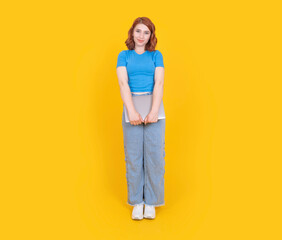 Fototapeta premium Cute woman holding laptop, full body view young 20s caucasian cute woman holding laptop wear casual jean and blue t shirt smiling looking camera isolated on yellow studio background, copy space.