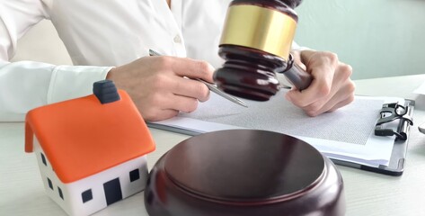 Judge is holding wooden gavel near toy house closeup