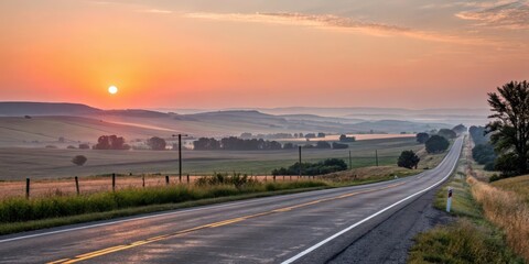 A scenic highway stretches towards a breathtaking sunrise over rolling hills and tranquil farmland