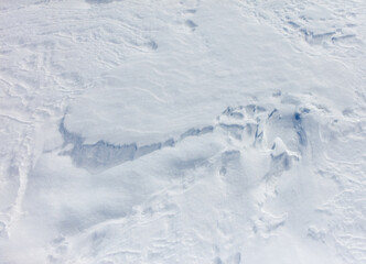 A snow covered ground with a few footprints