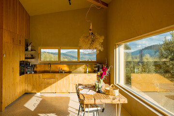 Sunlit kitchen with wooden cabinets and scenic mountain views through the window. A peaceful and inviting space for cooking and enjoying nature from indoors