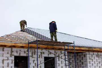 Two men are working on a roof of a house