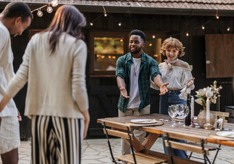 Friends welcoming guests to outdoor dinner party,
