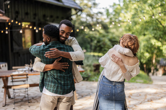Happy multiracial friends embracing at outdoor party