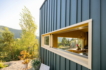 Perspective shot of an open window in a modern house, showcasing an elegant, nature-inspired interior. The lush greenery outside contrasts beautifully with the minimalist and cozy decor inside