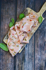 Slices Of  Traditional Italian antipasti mortadella Bolognese  on a wooden  cutting board.