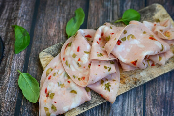 Slices Of  Traditional Italian antipasti mortadella Bolognese  on a wooden  cutting board.