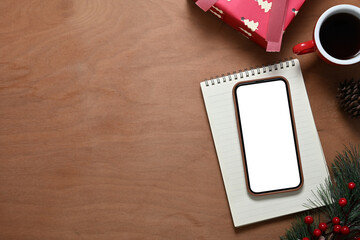 Smartphone with blank screen on wooden table with coffee cup pine branch and Christmas gift