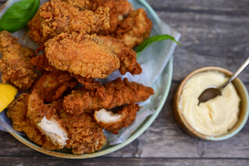 
 Crispy home made  deep fried   chicken strips . Breaded  with cornflakes chicken  breast fillets  with chilly peppers and fresh   basil on wooden rustic background